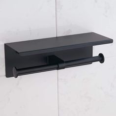 a black toilet paper holder on the wall