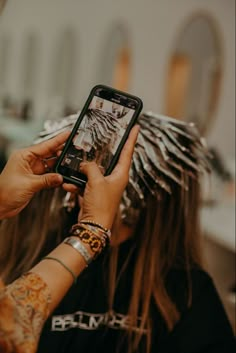 a woman with long hair is taking a photo on her cell phone while she's getting her hair done