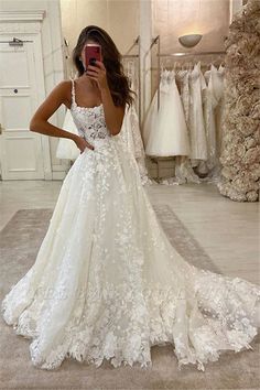 a woman in a wedding dress taking a selfie with her cell phone and looking at the camera