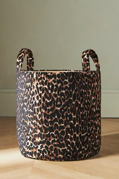 a leopard print basket sitting on top of a hard wood floor next to a wall