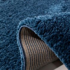 a close up view of a blue rug on the floor with an area rug underneath it