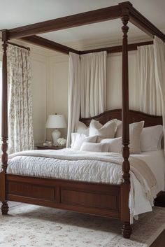 a four poster bed with white sheets and pillows