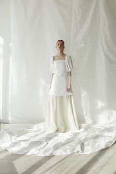 a woman standing in front of a white backdrop