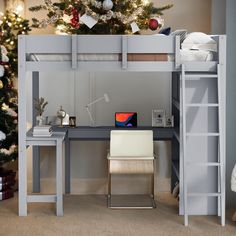 a loft bed with desk underneath and christmas tree in the background