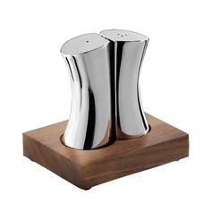 two stainless steel vases sitting on top of a wooden stand, one is turned upside down