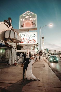 a bride and groom kissing in front of the little white chapel sign at night time