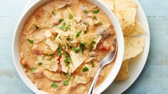 a bowl of soup with tortilla chips on a blue wooden table top, ready to be eaten