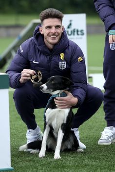 a man kneeling down next to a black and white dog