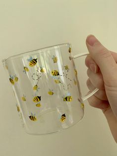 a hand holding a glass with bees on it