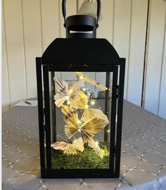 a lantern that is sitting on top of a table with grass and lights in it