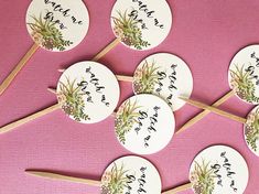 six round stick with flowers on them sitting on a pink tablecloth next to each other