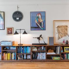 a living room with bookshelves and pictures on the wall above it, along with other decor items