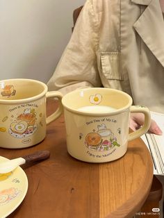 two coffee mugs with winnie the pooh designs on them sitting on a table