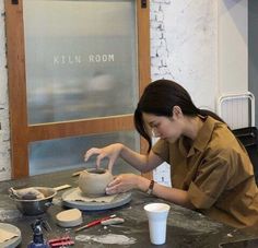 a woman is making pottery on a table