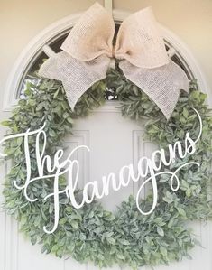 a wreath with the words the hangans on it and a bow hanging from the front door