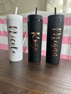 three black and white tumblers sitting on top of a wooden table