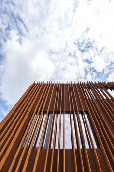 the top of a tall building with wooden slats on it's sides and sky in the background