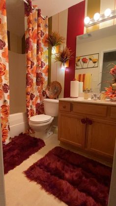 a bathroom with red rugs on the floor next to a toilet and sink in it