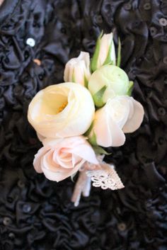 a bouquet of flowers sitting on top of a black lace covered table cloth with buttons