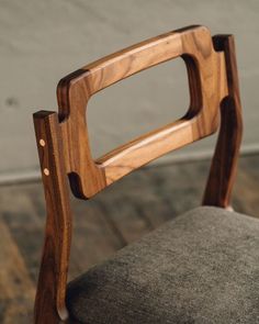 a wooden chair sitting on top of a hard wood floor next to a gray cushion