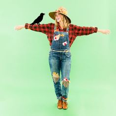 a woman wearing overalls and a hat with her arms outstretched