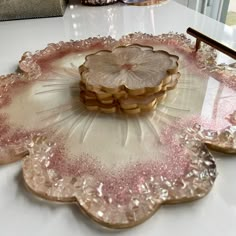 pink and gold glass plates on a white table with a brush in the middle, sitting on top of each other