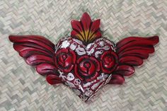 a red heart with wings on a woven surface