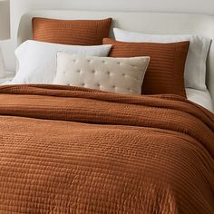 a bed with an orange bedspread and white pillows