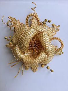 a close up of a flower made out of wickers and beads on a white surface