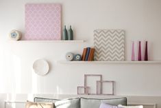 a living room filled with lots of furniture next to a wall mounted book shelf on top of a white wall