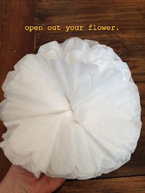 a hand holding a white paper ball on top of a wooden floor with the words open out your flower