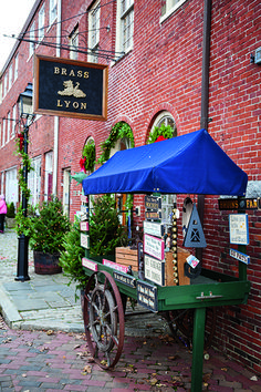 a small cart sitting on the side of a brick building with a blue umbrella over it