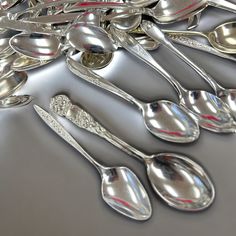 a bunch of spoons that are sitting on a table together with silverware in the middle