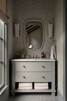 a bathroom with a sink, mirror and towels on the counter in front of it