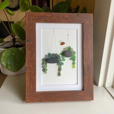 a wooden frame holding a painting with rocks and plants in it