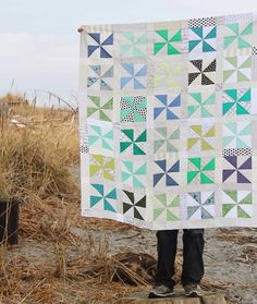 a person holding up a quilt on the beach