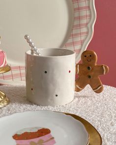 a white plate topped with a cup next to a gingerbread man and other decorations