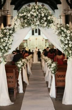 an aisle decorated with white flowers and greenery for a wedding ceremony at the church