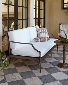 a white couch sitting on top of a checkered floor next to a glass door