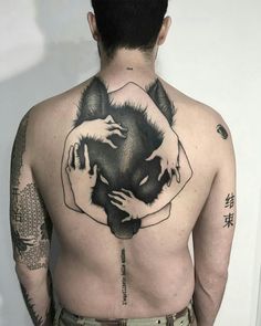 a man with a wolf tattoo on his back is holding onto another person's shoulder