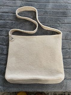 a white purse sitting on top of a gray blanket