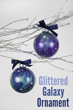 two ornaments hanging from branches with the words glittered galaxy ornament