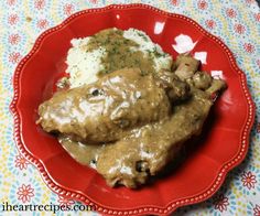 a red plate topped with meat covered in gravy