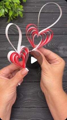 two hands holding red and white paper hearts