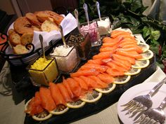 an assortment of food is displayed on a platter with silverware and forks, along with other foods