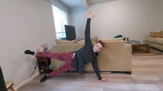 a woman laying on the floor in front of a couch with her arms up and legs spread out