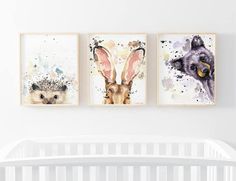 three animal prints hanging on the wall above a crib in a white nursery room