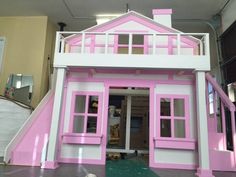 a pink and white doll house with stairs