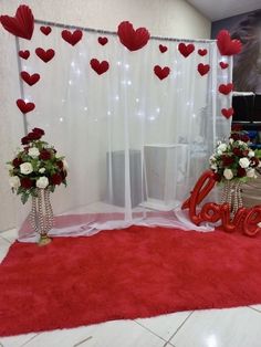 red and white flowers are on display in front of a curtain with hearts hanging from it