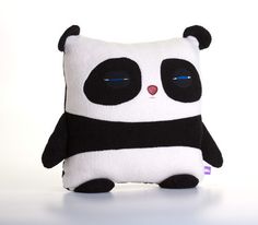 a small stuffed panda bear sitting on top of a white table next to a black and white pillow